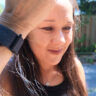 A woman holding up her arm with th Garmin CIRQA smart band.