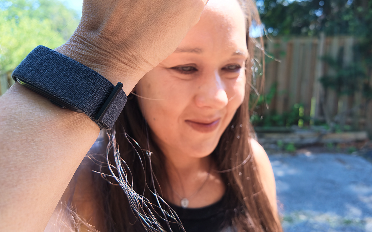 A woman holding up her arm with th Garmin CIRQA smart band.