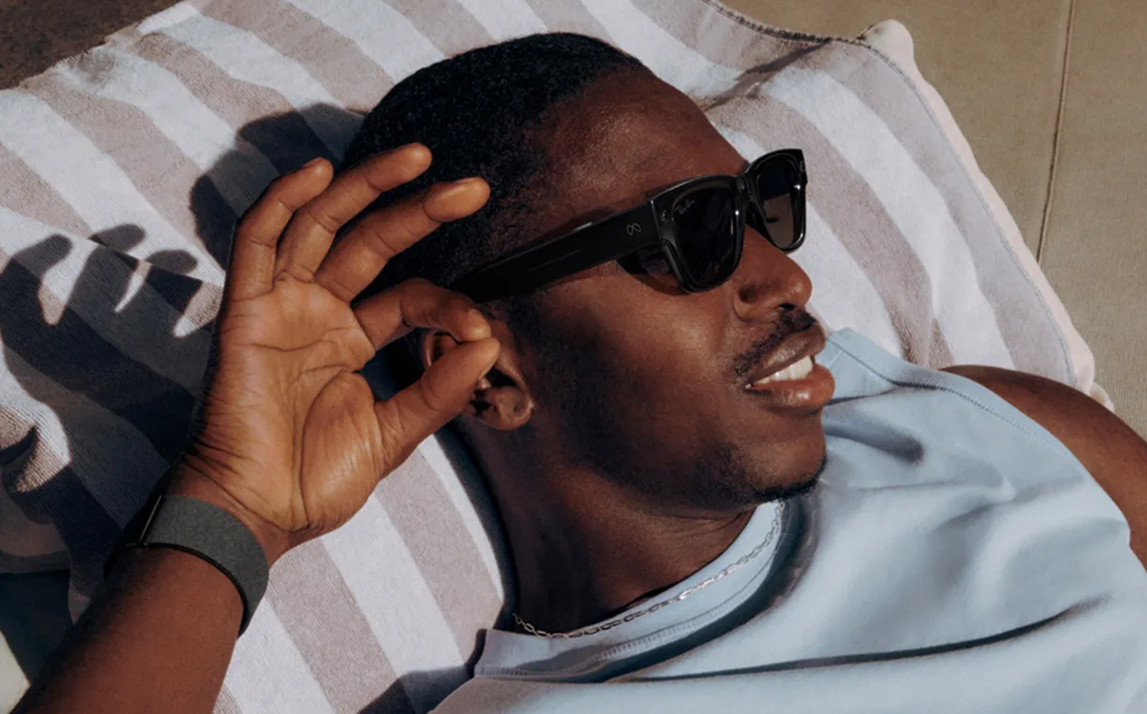 Man wearing Meta Ray-Ban Display Glasses with Neural Band lounging outside.