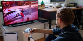 Gamer playing on PS5 with a DualSense wireless controller in front of a TV.