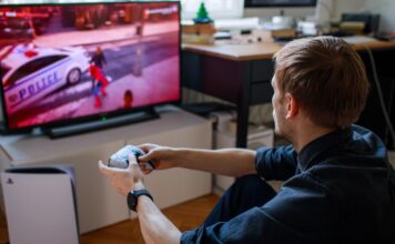 Gamer playing on PS5 with a DualSense wireless controller in front of a TV.