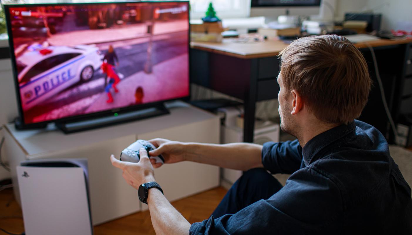 Gamer playing on PS5 with a DualSense wireless controller in front of a TV.