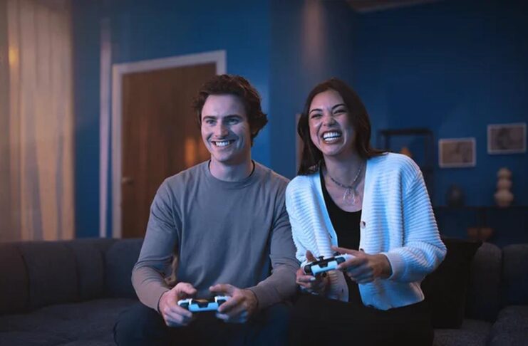 Two people playing PS5 with DualSense wireless controllers.