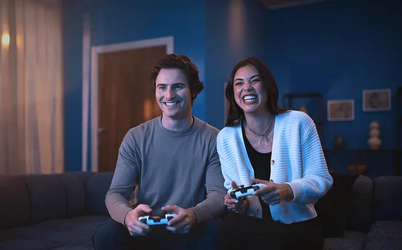 Two people playing PS5 with DualSense wireless controllers.