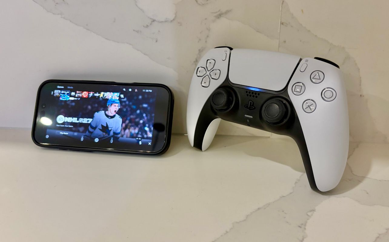 The PlayStation Remote Play app is working on an iPhone with the PS5 DualSense controller sitting next to it.