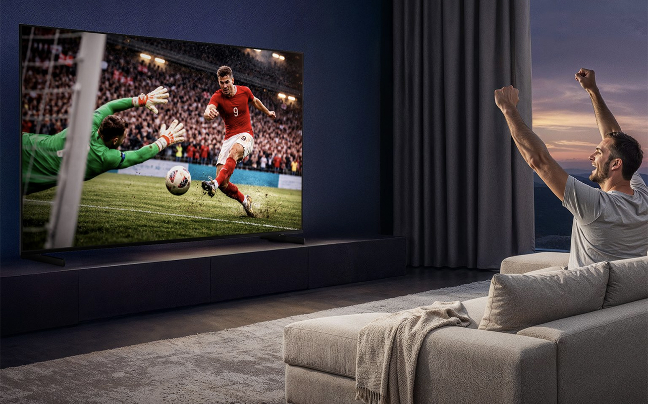A man cheering while watching football on a Samsung R85H TV.