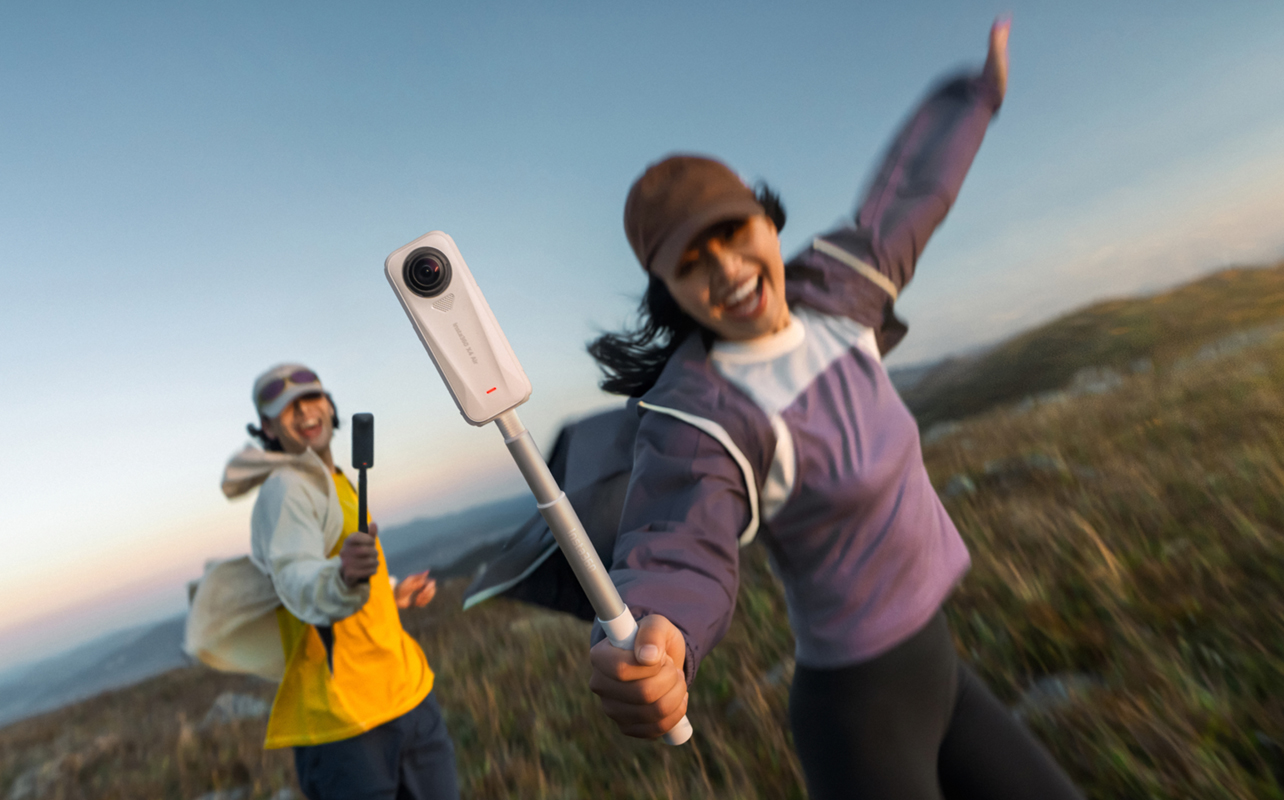 Woman holding Insta360 X4 Air running through a field.
