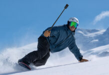 Man snowboarding holding an Insta360 X6.