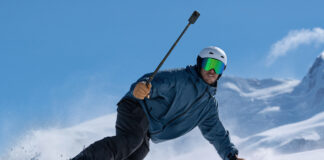 Man snowboarding holding an Insta360 X6.