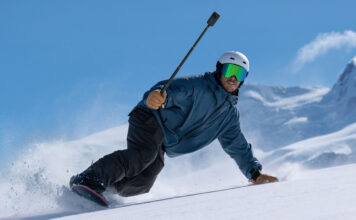 Man snowboarding holding an Insta360 X6.