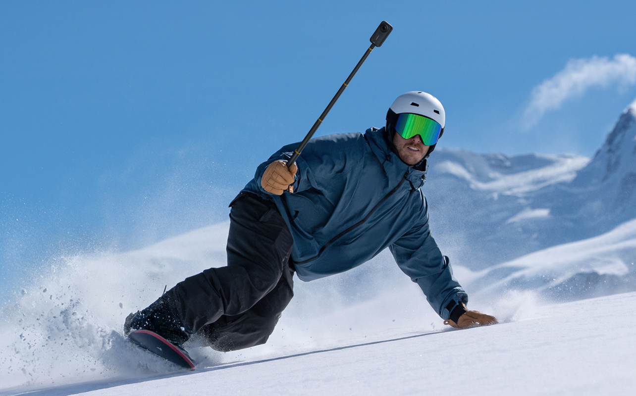Man snowboarding holding an Insta360 X6.