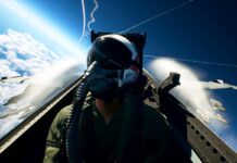 Ace Combat 8: Wings of Theve pilot seated in a fighter jet cockpit above the clouds with aircraft flying nearby.