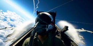 Ace Combat 8: Wings of Theve pilot seated in a fighter jet cockpit above the clouds with aircraft flying nearby.