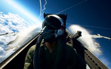 Ace Combat 8: Wings of Theve pilot seated in a fighter jet cockpit above the clouds with aircraft flying nearby.