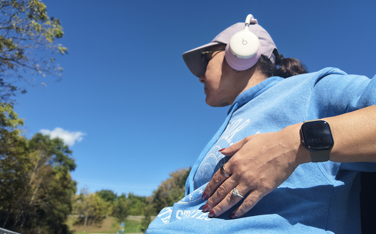 A woman sitting on a bench outside wearing the Apple Watch Series 12.