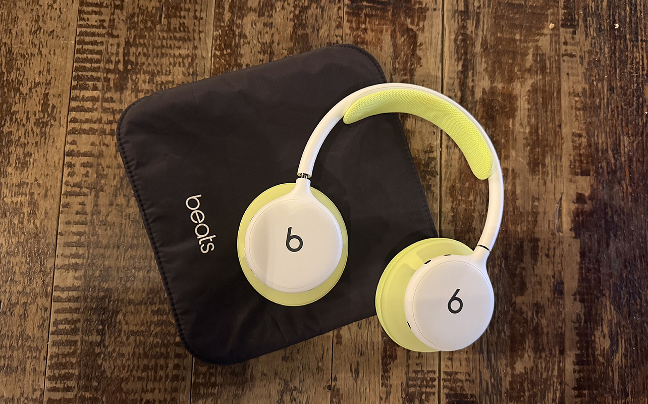 The Beats 360 headphones with green ear cushions sitting atop the case.