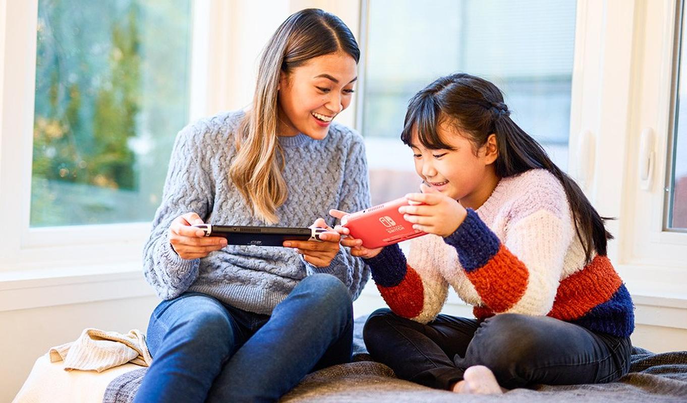 Two people playing Nintendo Switch together with handheld systems.