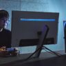 Gamer wearing a Sony INZONE headset while using a controller in front of a gaming monitor.