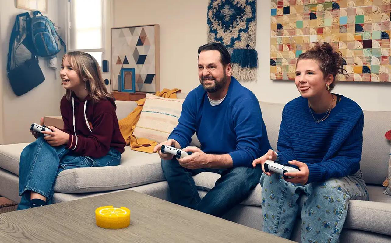 Three people playing PS5 games together with DualSense wireless controllers.