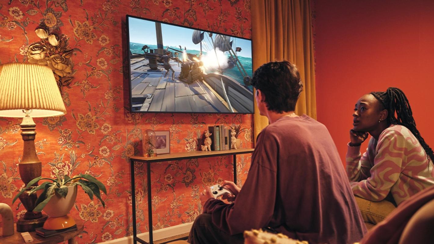 Two people playing XBOX on a TV with an XBOX Wireless Controller.
